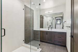 Bathroom with vanity, tile patterned floors, and a shower with door