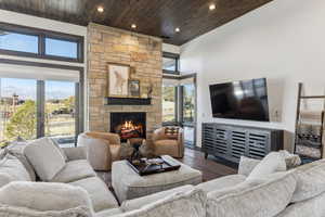 Living room with hardwood / wood-style floors, wooden ceiling, a fireplace, and a high ceiling