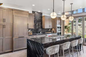 Kitchen with pendant lighting, plenty of natural light, a center island, and dark stone counters