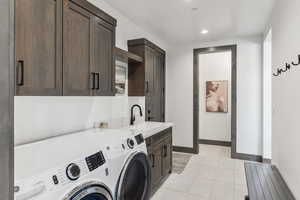 Laundry area with washing machine and dryer, sink, light tile patterned floors, and cabinets