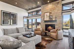 Living room with wood-type flooring, a fireplace, wood ceiling, and a towering ceiling