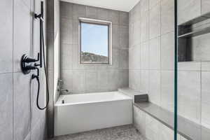 Bathroom featuring tile patterned floors, tile walls, and a bathing tub