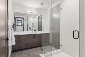 Bathroom with tile patterned floors, a shower with door, and vanity