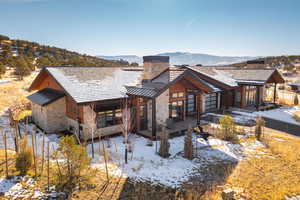 Snow covered back of property with a mountain view