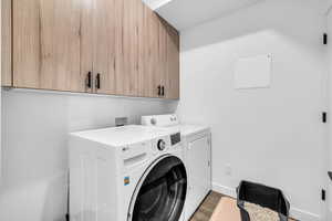 Laundry room featuring cabinets, washing machine and dryer, dark wood-type flooring and maintenance closet