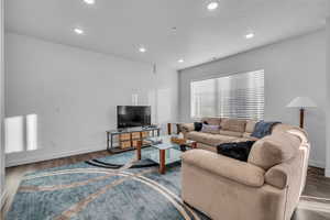 Generous living room with dark hardwood / wood-style flooring and lots of natural light