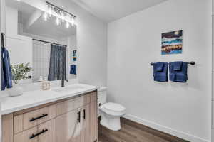 Bathroom with a tub / shower, vanity, toilet, and wood-type flooring