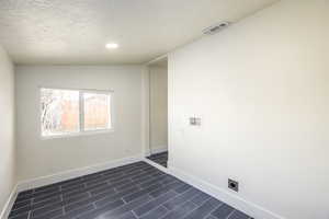 Clothes washing area featuring hookup for an electric dryer, a textured ceiling, and hookup for a washing machine