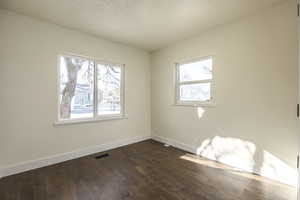 Unfurnished room with dark hardwood / wood-style flooring and a healthy amount of sunlight