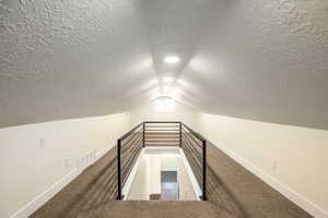 Bonus room with carpet, a textured ceiling, and lofted ceiling