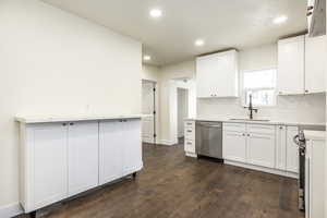 Kitchen featuring white cabinetry, sink, tasteful backsplash, dark hardwood / wood-style floors, and appliances with stainless steel finishes