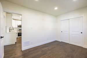 Unfurnished bedroom with dark hardwood / wood-style flooring, sink, and a closet