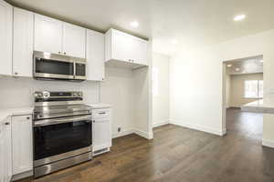 Kitchen featuring white cabinetry, dark wood-type flooring, and appliances with stainless steel finishes