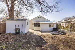 Back of property featuring central AC unit and a storage unit