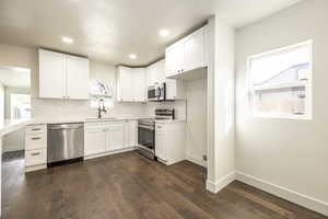 Kitchen featuring white cabinetry, sink, tasteful backsplash, dark hardwood / wood-style flooring, and appliances with stainless steel finishes