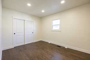 Unfurnished bedroom featuring dark hardwood / wood-style flooring and a closet