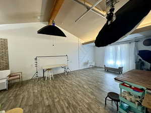 Interior space with vaulted ceiling with beams, hardwood / wood-style floors, and a textured ceiling