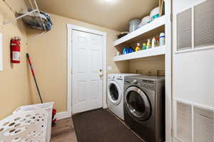 Clothes washing area featuring washer and clothes dryer and dark hardwood / wood-style floors