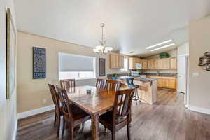 Dining room with wood-type flooring, vaulted ceiling, and a notable chandelier