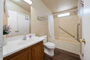 Full bathroom with shower / bathtub combination with curtain, wood-type flooring, lofted ceiling, toilet, and vanity