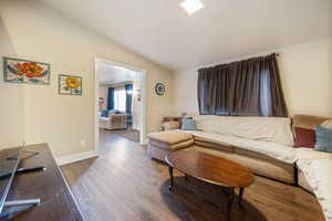 Living room with vaulted ceiling and hardwood / wood-style flooring