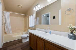 Full bathroom featuring lofted ceiling, toilet, vanity, shower / tub combo, and hardwood / wood-style flooring