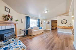 Living room with hardwood / wood-style floors, a textured ceiling, and vaulted ceiling