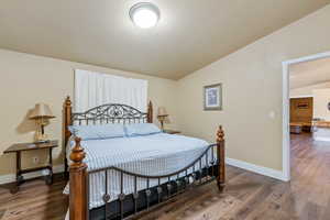 Bedroom featuring a textured ceiling, dark hardwood / wood-style flooring, and lofted ceiling