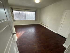 Spare room featuring dark hardwood / wood-style flooring and a baseboard heating unit