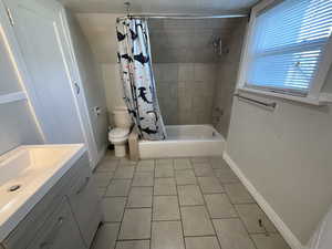 Full bathroom featuring tile patterned floors, shower / bath combo, toilet, and vanity