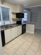 Kitchen featuring black appliances, sink, built in features, light tile patterned floors, and tasteful backsplash