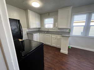 Kitchen with sink, dark hardwood / wood-style floors, backsplash, white cabinets, and black appliances