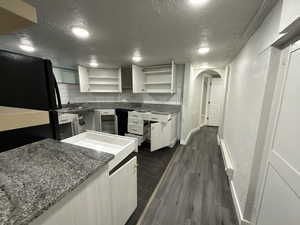 Kitchen featuring backsplash, dark stone countertops, white cabinetry, and dark wood-type flooring