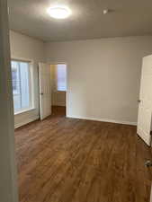 Empty room with dark wood-type flooring and a textured ceiling