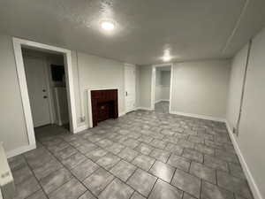 Interior space featuring a textured ceiling and a tiled fireplace