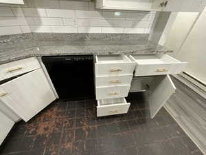 Kitchen with white cabinetry, decorative backsplash, stone counters, and black dishwasher