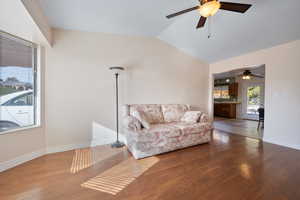 Living room with wood-type flooring, ceiling fan, and lofted ceiling