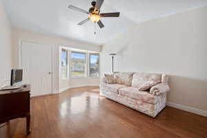 Living room featuring ceiling fan, hardwood / wood-style floors, and lofted ceiling