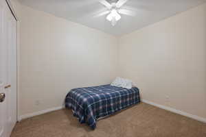 Carpeted bedroom with ceiling fan and a closet