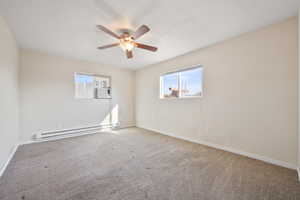 Unfurnished room with carpet flooring, baseboard heating, and ceiling fan