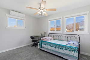 Bedroom with carpet flooring, ceiling fan, and a wall mounted air conditioner