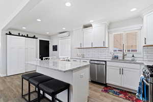 Kitchen with appliances with stainless steel finishes, wood style tile flooring, a kitchen breakfast bar, a barn door, and a center island