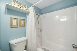 Bathroom featuring toilet and shower / bath combo with shower curtain