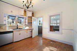 Kitchen with white cabinets, hardwood / wood-style flooring, stainless steel dishwasher, and sink