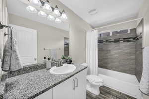 Full bathroom with hardwood / wood-style floors, vanity, toilet, and shower / bath combo with shower curtain