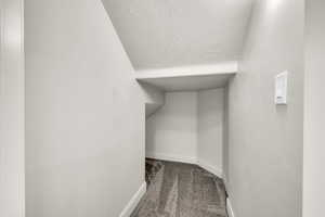 Interior space with a textured ceiling, carpet floors, and lofted ceiling