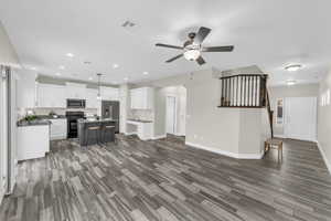 Unfurnished living room featuring ceiling fan, dark hardwood / wood-style flooring, and sink