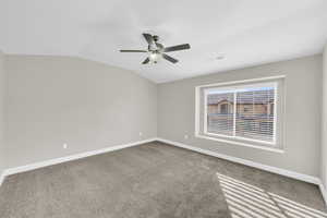 Spare room with ceiling fan, carpet, and vaulted ceiling