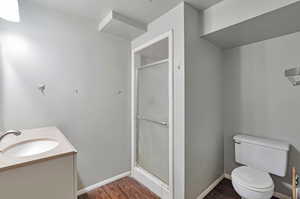 Bathroom featuring hardwood / wood-style floors, vanity, a shower with door, and toilet