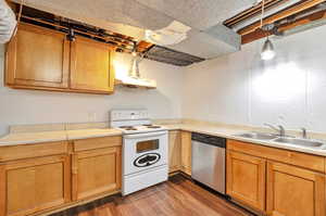 Kitchen featuring dishwasher, sink, hanging light fixtures, dark wood-type flooring, and white range